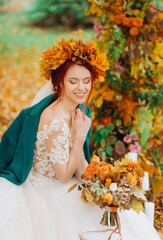 The bride in an autumn wreath sitting on an easy chair in the park