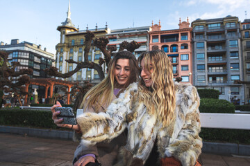 Two girls chatting sat on a bench at Donostia-San Sebastian; Basque Country.