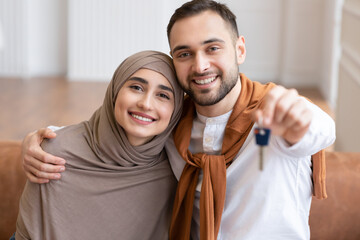 Fototapeta premium Happy Muslim Family Couple Showing New House Key Sitting Indoors
