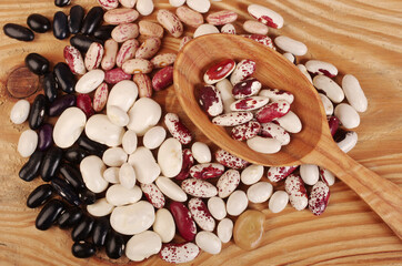 Various types of beans on a wooden table.