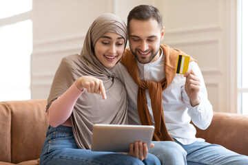 Excited Muslim Couple Shopping Online With Digital Tablet At Home