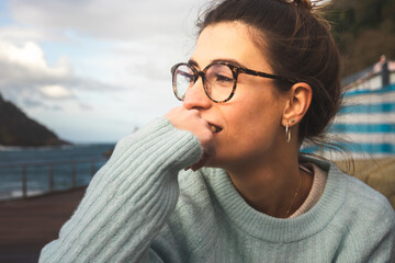 Portrait of a young caucasian girl sat on a bench at the sea side on Donostia-San Sebastian; Basque Country.