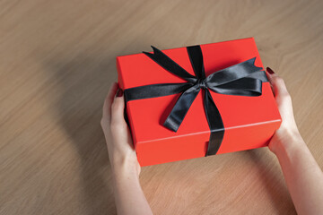 A woman holding a red gift box between her hands. Happy valentine’s day, red color, heart icon, isolated background