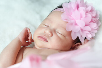 A beautiful newborn girl wearing a pink headband and sleeping on a white soft blanket, Infant, babyhood concept and copy space - Image