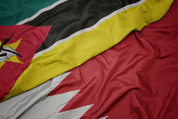 waving colorful flag of bahrain and national flag of mozambique.