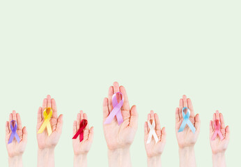 Hands hold multicolored ribbons, symbol of the fight against cancer. World cancer day