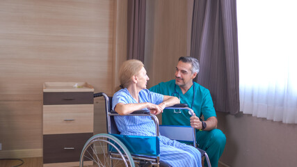 Fototapeta na wymiar Doctor taking care of mature female patient sitting on wheelchair