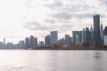Obraz premium Roosevelt Island and Manhattan Skyline along the East River during Autumn with Colorful Trees in New York City