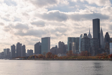 Fototapeta premium Roosevelt Island and Manhattan Skyline along the East River during Autumn with Colorful Trees in New York City