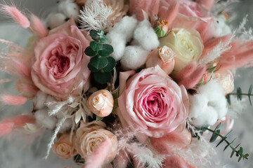 A bouquet of flowers of pink shades of roses and dried flowers in a gift box.