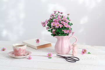 Obraz na płótnie Canvas Romantic breakfast scene with pink flowers, a cup of coffee and a book. Cottage home table setting
