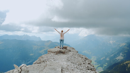 Happy free woman with outstretched hands on the top on the rock. Enjoying nature and feeling free.