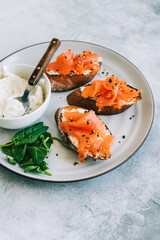 Delicious toast with salmon and cheese cream on a white plate whit spinach.
