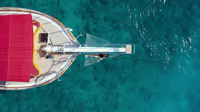 Girl in bikkini lies hammock on the bow of a yacht against the backdrop of the sea. Aerial view 4K.