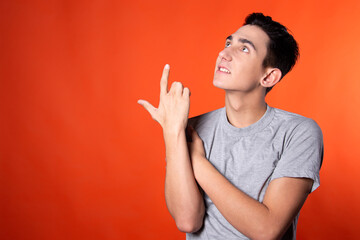 The young man is actively gesturing. Expression of emotions. Blue clothes. Orange background. Point of view.