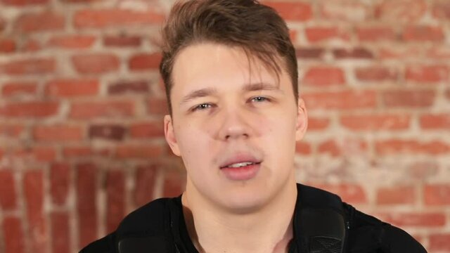 Portrait of a guy after doing the exercise dyspnea. He breathes heavily through his mouth, looks at the camera. Rest during training. Respiration restoration.