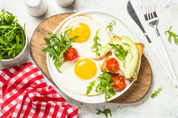 Breakfast. Fried egg, toast with salmon and avocado and fresh salad. Healthy food. Top view with copy space at white stone table.