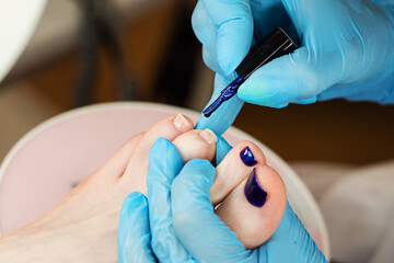 Process pedicure close up. Unrecognizable people. Master chiropody applying gel nail polish. Spa....