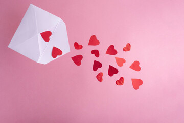 Red hearts flying out of a white envelope on a pink background