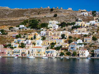 Fototapeta na wymiar houses, buildings and castle with yachts and boats in the port town of Simi a Greek island in the Aegean