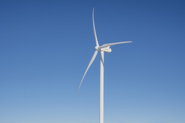 Close-up view of a wind turbine on a blue sky