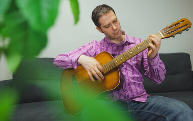 Obraz premium Handsome man playing nylon guitar at home.