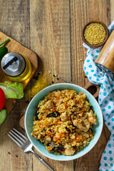 Bulgur with turkey and prunes is served with fresh vegetable on a rustic table. Top view flat lay. Copy space.