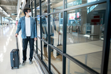 Asian man tourist wearing face mask carrying suitcase luggage looking at closed restaurant in...