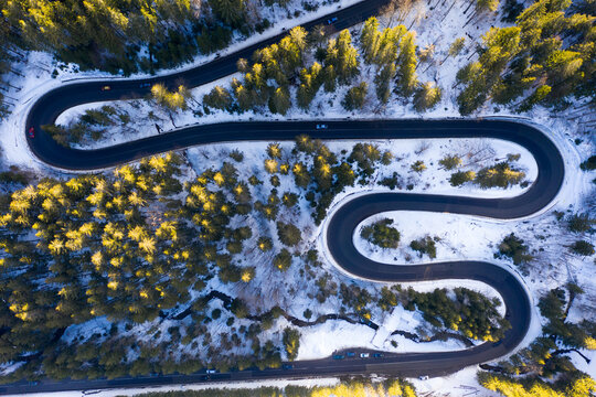 Aerial drone photograph bird's eye perspective of a beautiful winding mountain road in Romania in winter time