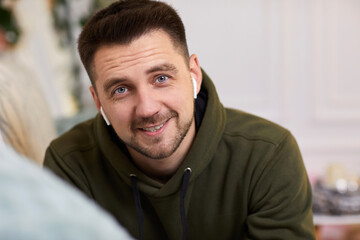 portrait of smiling handsome young man in earphones is talking to somebody on video call