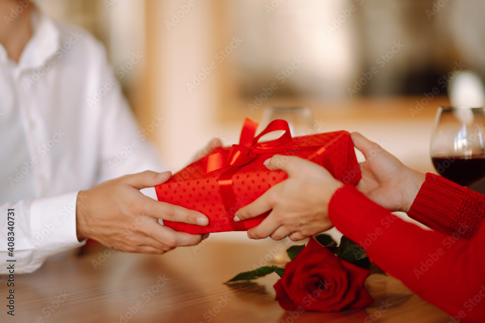 Wall mural Exchange of gifts.  Young couple in love offering gift to each other for valentine day or birthday. Romantic day. Winter holidays.