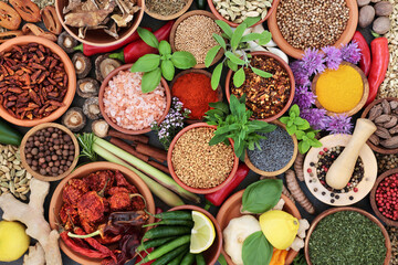 Herb and spice assortment in bowls forming a colourful abstract background. Flat lay, top view.