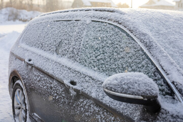 Samochód zasypany śniegiem na parkingu zimową porą, auto przykryte białym puchem śnieżnym - obrazy, fototapety, plakaty