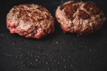 Carne de hamburguesa casera a medio cocinar en una sartén negra