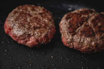 Hamburguesa de carne cruda en sartén negra con aceite