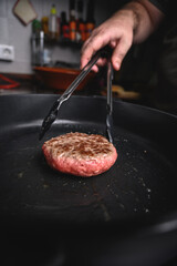 Hamburguesa de carne cruda en sartén negra con aceite