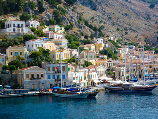 Fototapeta na wymiar houses, buildings and castle with yachts and boats in the port town of Simi a Greek island in the Aegean