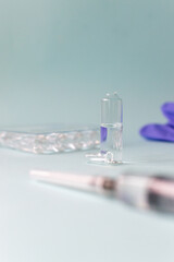 A bottle with a vaccine with a dose of medication on a blue background. Vaccination. COVID-19, SARS - CoV2 Vaccine concept. Copy space. Vertical orientation.