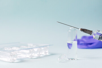 Several doses of vaccine and a syringe with medicine on a blue background. Vaccination. COVID-19, SARS - CoV2 Vaccine concept. Copy space. Horizontal orientation.