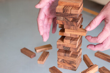 Selective focus at wood brick. Business people using hand to pull out wood brick with caution. taking risk and make decision to play the game. Insurance or financial risk management and safety concept
