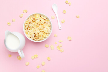 Corn flakes with milk in jar and spoon on pink background