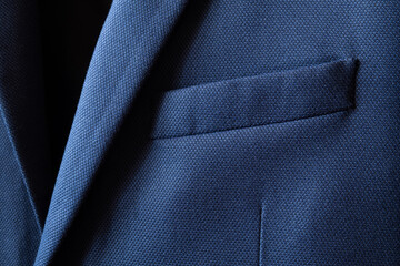 High resolution with details and quality shot of formal dark blue wool suit fabric texture. with front pocket decoration under light and shadow ambient. Ideal for background or wallpaper.