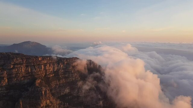 Landscape, normal speed &ndash; colorful moving clouds in evening time from above on Table Mountain with Table Mountain&rsquo;s cliffs on the left side, Cape Town, South Africa