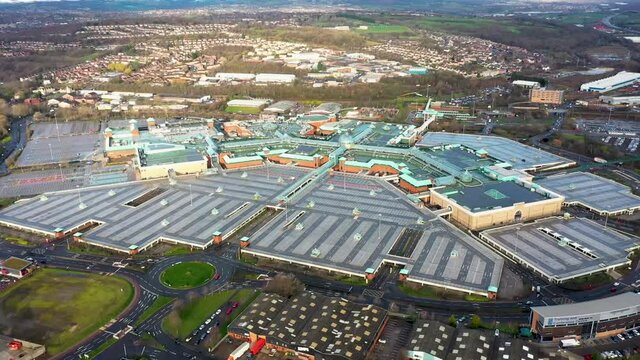 Aerial footage of a large shopping centre known as Meadowhall, it's a indoor shopping centre in Sheffield, South Yorkshire, England showing the empty car park parking lot and glass roof