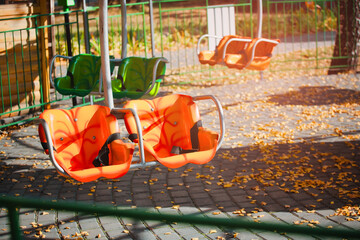 Empty seats of the amusement park attraction. Deserted autumn park. The end of the entertainment...