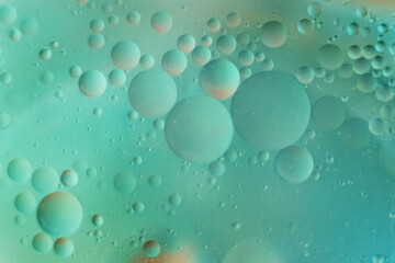 Macro photo of oil droplets in water on a green blue blurred background