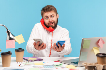 Scared man office worker answering calls at workplace all covered with sticky notes and holding...