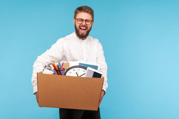 Extremely happy man with beard in eyeglasses and white shirt smiling holding big cardboard box with his stuff, getting new job or job promotion
