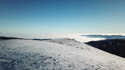 A drone shot of snow capped Alps in the region of Speikkogel in Austrian Alps. The whole are is covered with snow. Many mountain chains in the back. Thick fog in the valley. Winter outdoor activity.