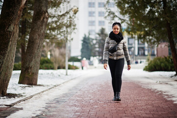 African woman wear in black scarf walks on the path in winter day at Europe.